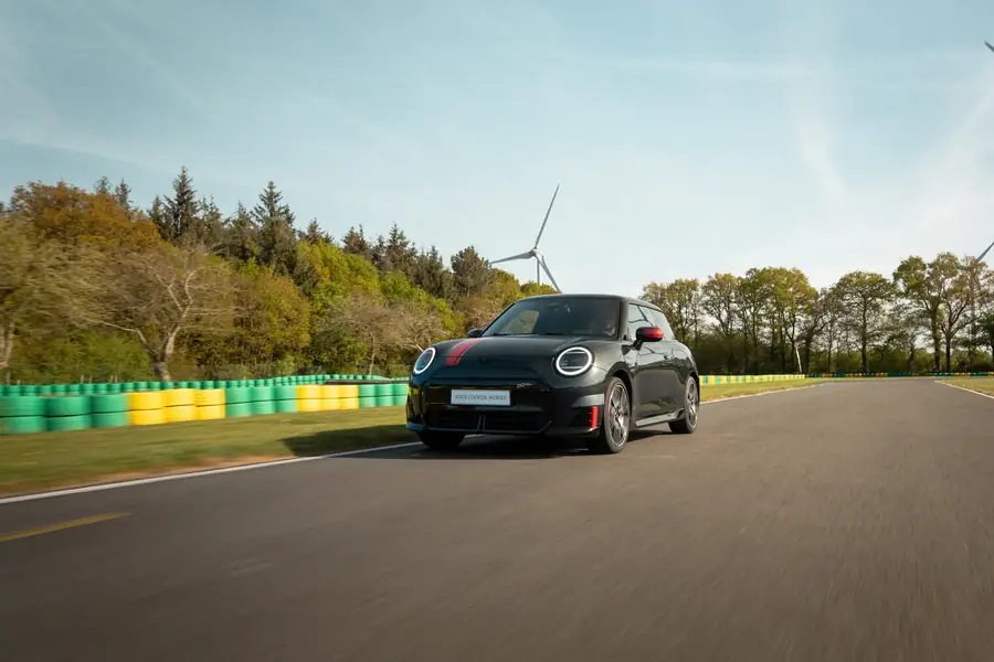 Mini Cooper électrique noire sur piste de course, éoliennes en arrière-plan — Lucas Gouritin