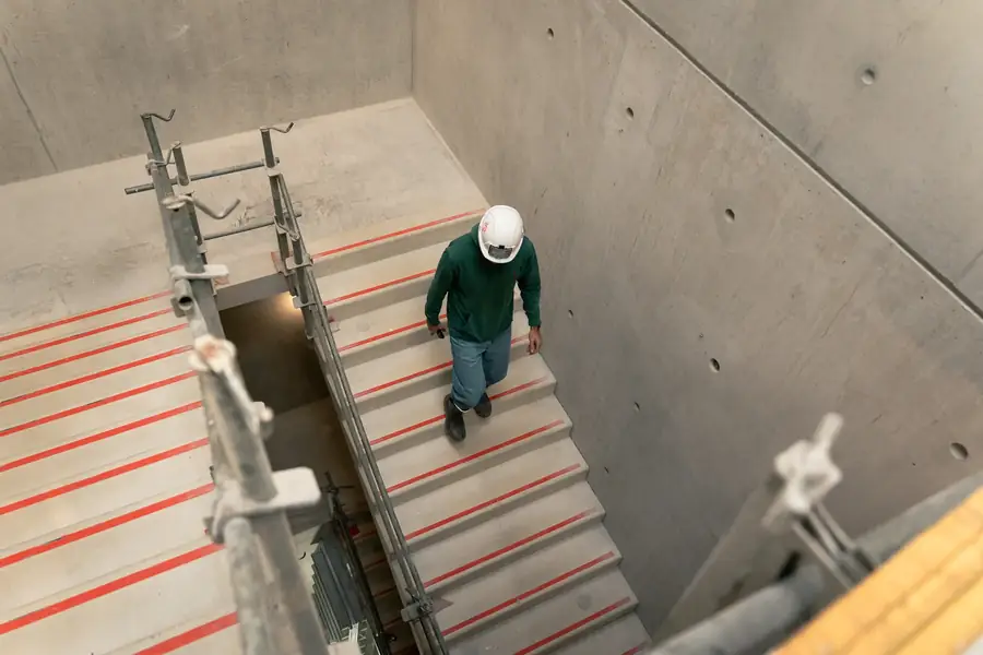 Ouvrier en casque sur un escalier en béton brut de chantier — Lucas Gouritin