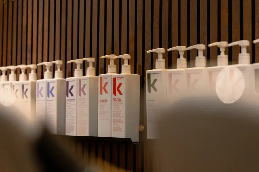 Flacons de produits capillaires professionnels alignés sur un mur en bois — Lucas Gouritin