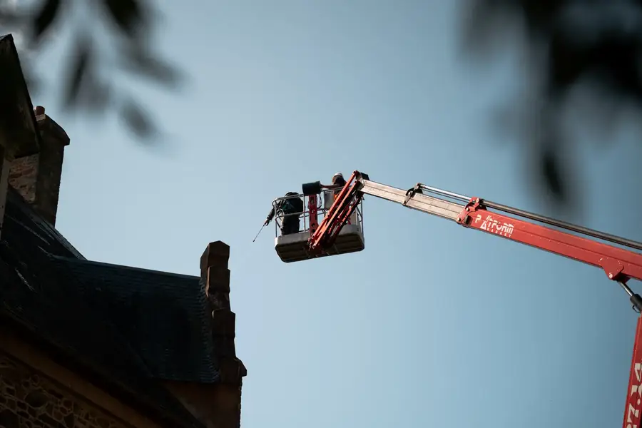 Ouvrier dans une nacelle élévatrice nettoyant la façade d'un bâtiment ancien — Lucas Gouritin