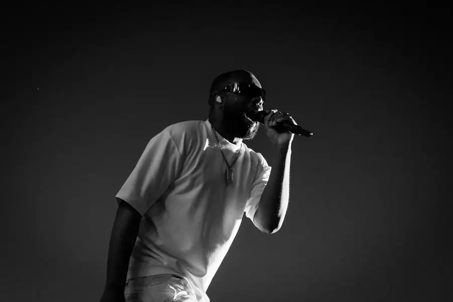 Artiste en concert chantant au microphone, ambiance sombre et lumineuse — Lucas Gouritin