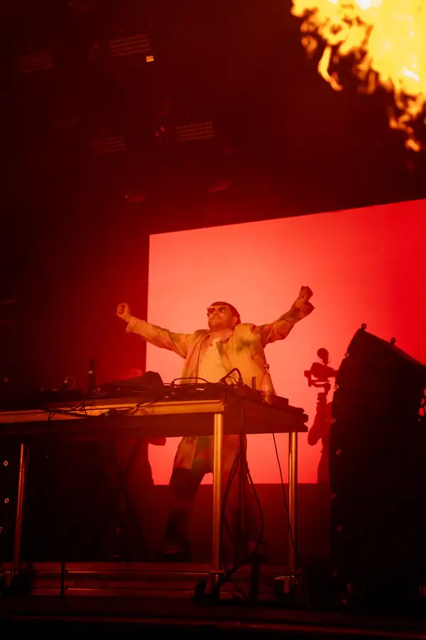 DJ sur scène, bras levés, flammes et lumières rouges au concert — Lucas Gouritin