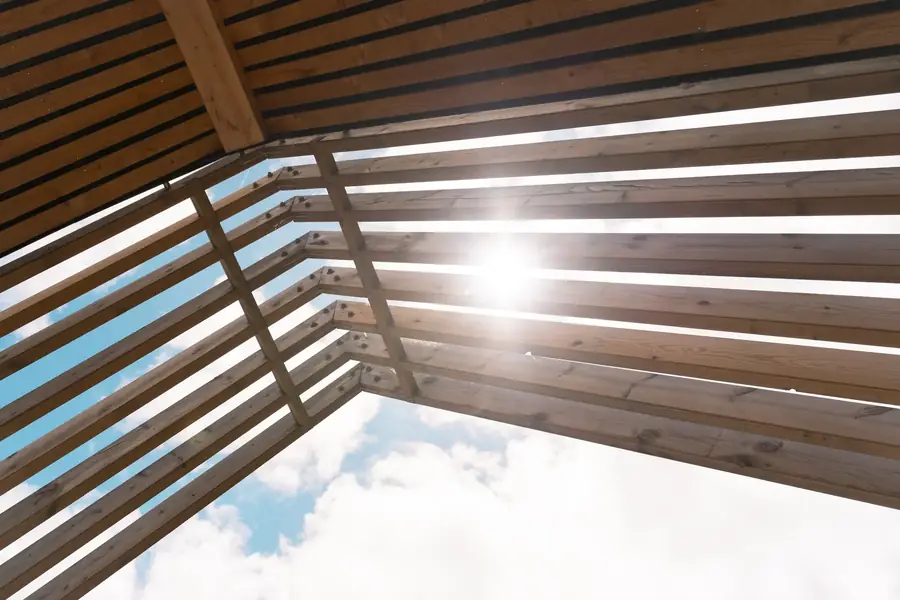 Lumière du soleil filtrant à travers une pergola en bois, ciel bleu — Lucas Gouritin